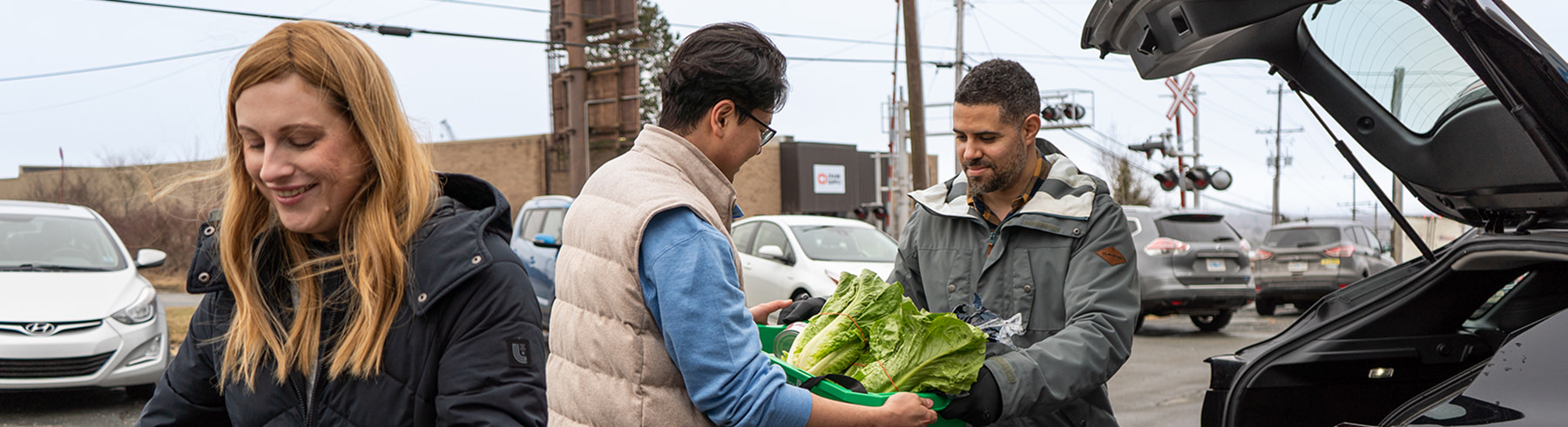 A person handing a basket of vegetables to another