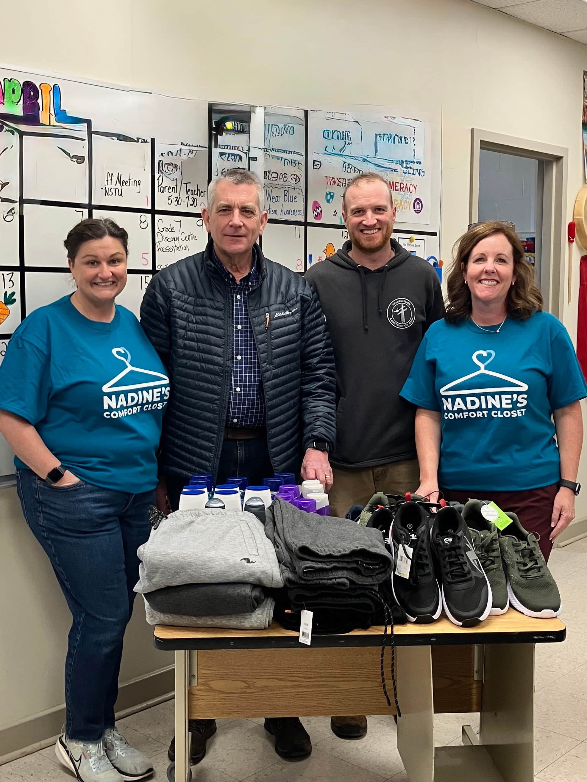 A few people standing behind a table with some clothes on it