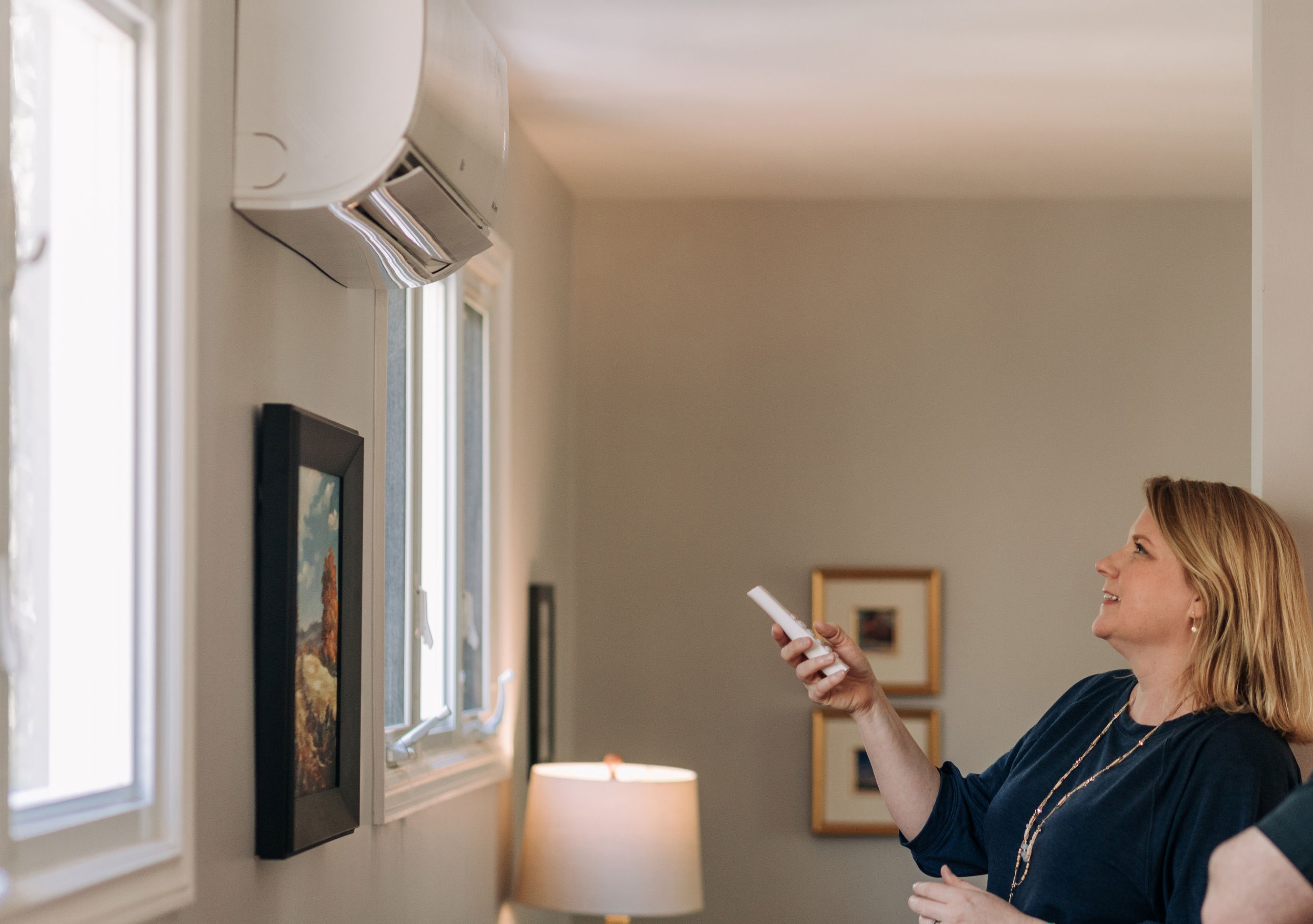 Residential customer pointing remote control at a heat pump